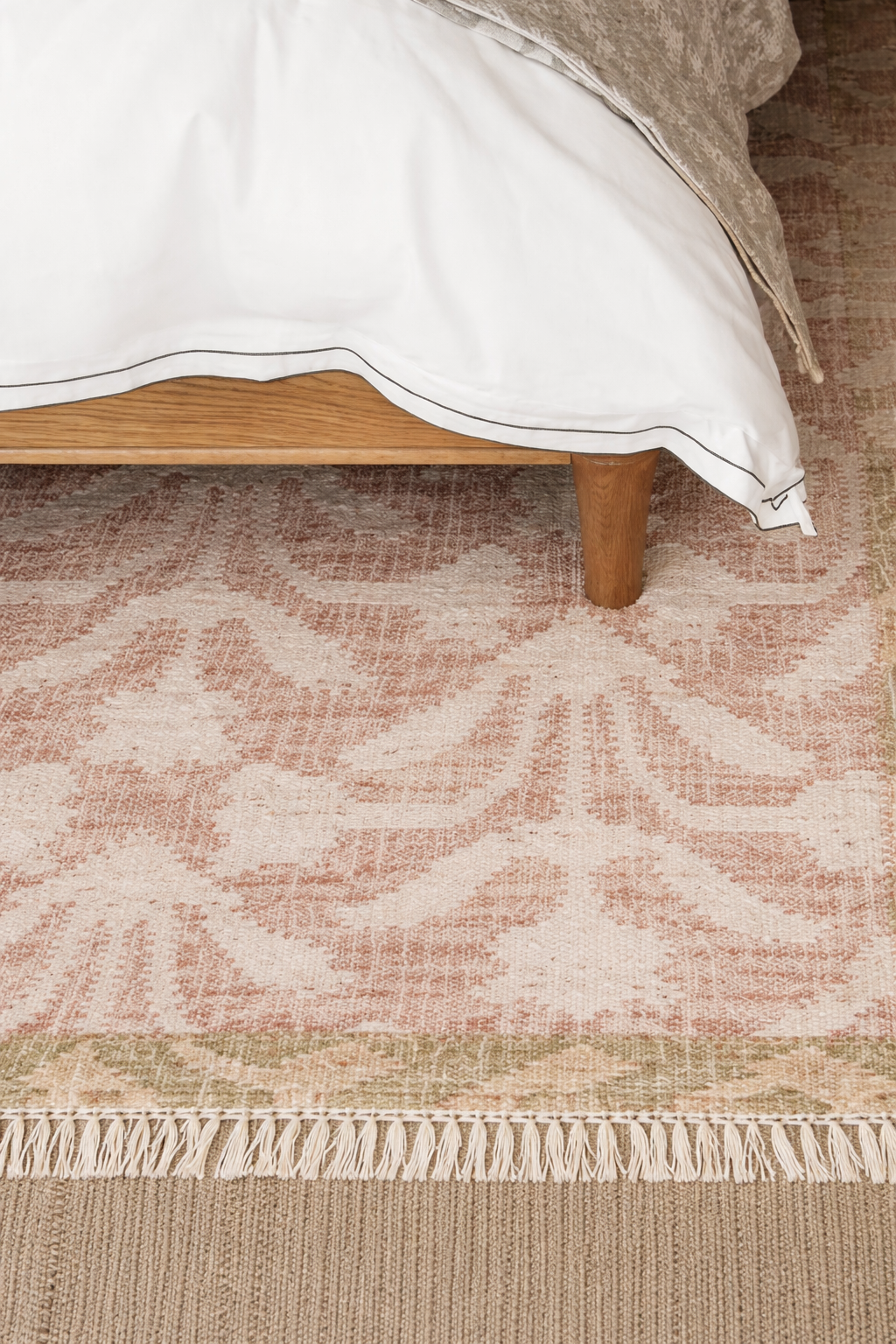 Patterned rug with a bed in the background